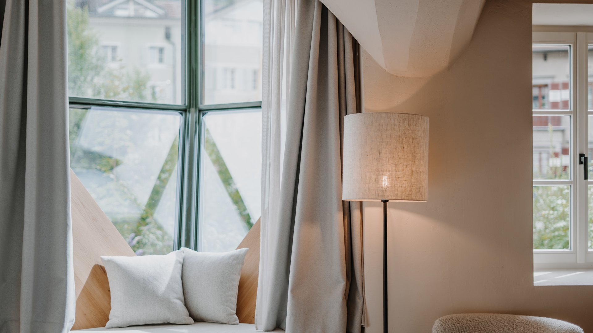 Cozy seating area with cushions by a window and floor lamp