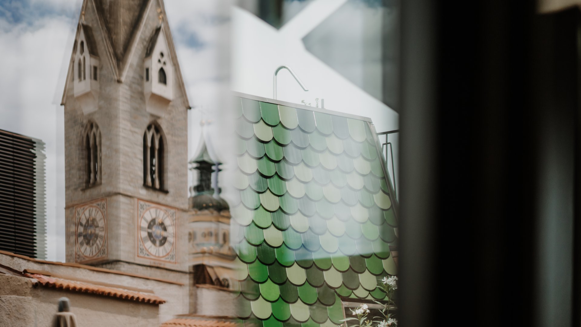 Reflection of church tower and green tiled roof seen through window